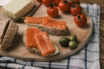 Two sandwiches with smoked salmon and cream cheese on old board on rustic wooden background. Top view