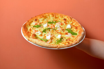 Whole pizza on hand over pastel colored background. Delicious Italian pizza with cheese. Creative idea concept.