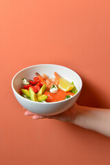 Italian salad with salmon, shrimps and avocado on hand over pastel colored background. Delicious Italian cuisine concept