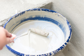 Eimer Farbe mit einer Rolle in der Hand