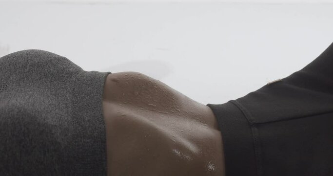 Sweat droplets on the stomach of a fit woman doing stomach crunches