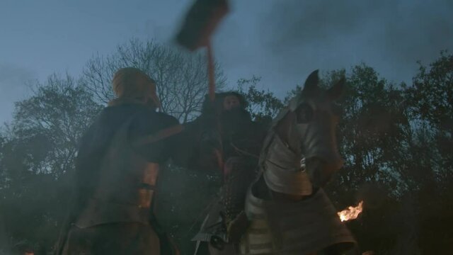 Soldier in fiery medieval battle knocks enemy from horse with war hammer