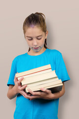A little girl holds stack of school books