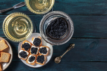 Caviar, champagne, luxury gourmet food, vintage style, overhead shot on a dark wooden background...
