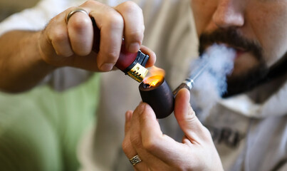Close-up of a young red-haired bearded man
close up of man smoking tobacco pipe
Cradle for smoking. Cropped image of a handsome guy with a beard and a ring on his finger lights a cigarette and smokes 