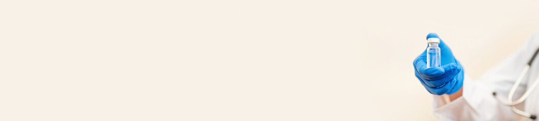 Doctor or nurse holding hands flu vaccine on beige background, measles injection syringe for baby, man, woman vaccination, medicine and drug concept. Vaccination against Coronavirus covid-19 pandemic