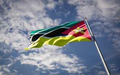 Mozambique national flag waving at sky background close-up.