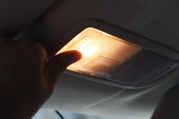 Closeup photo of woman turning light on in car salon. Turn on the light in the car