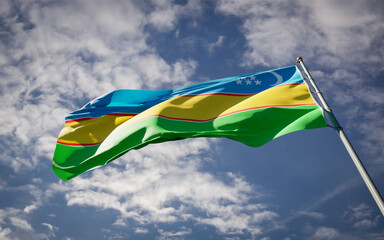 Karakalpakstan national flag waving at sky background close-up.