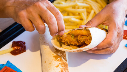Wrapped burritos with fresh vegetables and fried chicken.