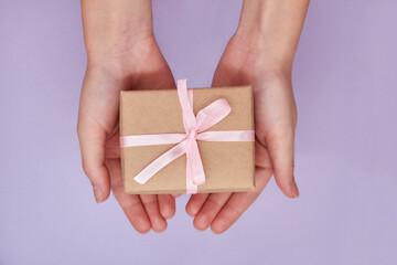 Girl holding in hands Christmas or New Year gift box against a purple background