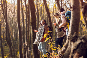 Obraz na płótnie Canvas Three female friends having fun and enjoying hiking in forest on a beautiful autumn day.