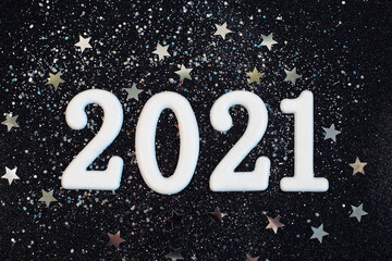Happy New year 2021 with silwer glitter stars on black background.