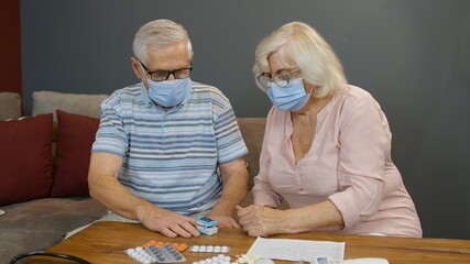 Senior couple grandfather and grandmother measuring, monitoring oxygen saturation with digital...