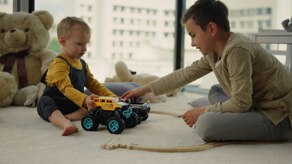 Nice kids sharing toy cars on carpet. Amazing kids playing together indoors.