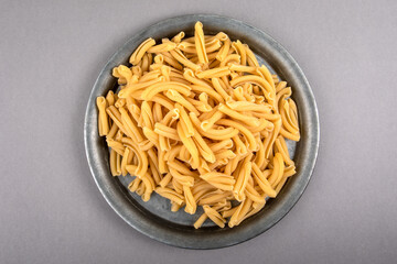 Strozzapreti, Italian pasta in metal plate on a gray table