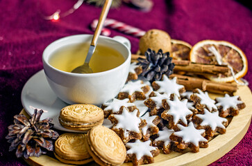 Homemade Christmas cookies stars from nuts and dates on a wooden tray, next to a mug of coffee, New Year's decor of pine cones and garlands. Cozy winter tea party, sweet new year food gift