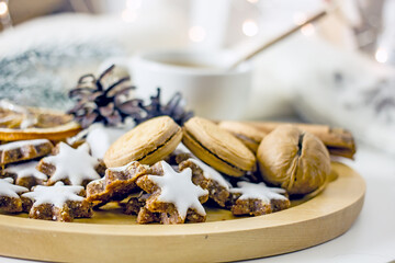Homemade Christmas cookies stars from nuts and dates on a wooden tray, next to a mug of coffee, New Year's decor of pine cones and garlands. Cozy winter tea party, sweet new year food gift