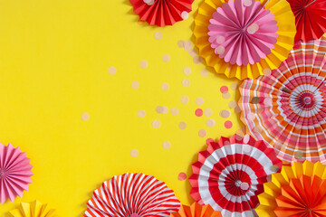 Colorful paper rosette and birthday garlands. Decorating for a party. Round, bright and color decoration. Yellow background.