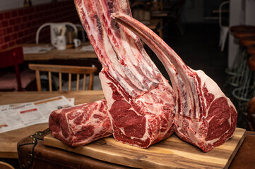 Tomahawk Steaks dryaged auf Holzbrett im Restaurant mit Metrofliesen