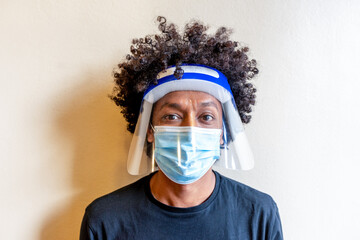 portrait of a hairdresser with all the protections on the face to be able to exercise the profession safely during the virus crown, facial protective shield, surgical mask, happy eyes