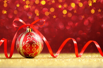 Red christmas ball with red bow on golden glitter