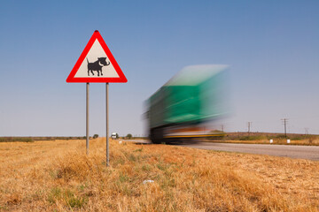 Truck passes a road sign to warn of warthogs on the road