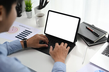 Cropped shot of businessman is working on computer tablet and checking financial report and charts at the workplace.