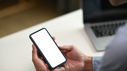 Cropped shot of professional businessman holding blank screen smartphone in modern office room.