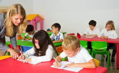 Young teacher woman and diligent schoolkids during lesson in classroom..