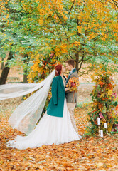 Obraz na płótnie Canvas Wedding ceremony in the autumn park. The newlyweds standing near the decorated arch.