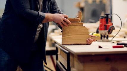 Bearded kraft caucasian man in a carpentry workshop with sandpaper polishes a cutting board made of handmade wood, concept handcraft and craftsmanship