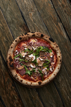 Close up on delicious freshly baked small pizza with melted cheese mushrooms and arugula