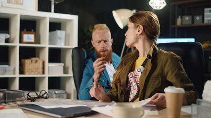 Business people working documents in late office. Hipster couple talking indoors