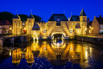 Old city gate Koppelpoort in Amersfoort city, the Netherlands during sunset. Two towers are connected to an arch gate.