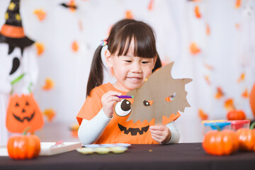 young girl painting witch mask for halloween party at home