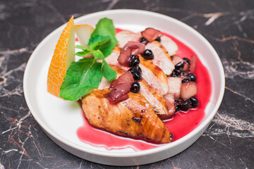 Delicious and juicy chicken with melon and berries on a white plate