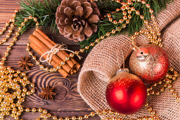 Christmas composition, red balls and gold beads, cinnamon, star anise, fir branches, New Year's decor on a wooden background.