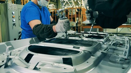 Car manufacturing workers using structural adhesive at a car factory