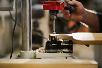 Bearded kraft caucasian man in a carpentry workshop with a drilling machine handcrafted wood board, concept handicraft and craftsmanship close up