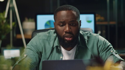 Upset afro businessman reading bad news in office. African man working laptop