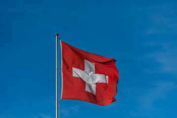 Schweizer flagge weht im Wind an blauem Himmel