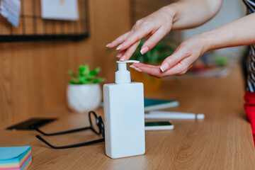 Fototapeta na wymiar Female hands using sanitizer in the office