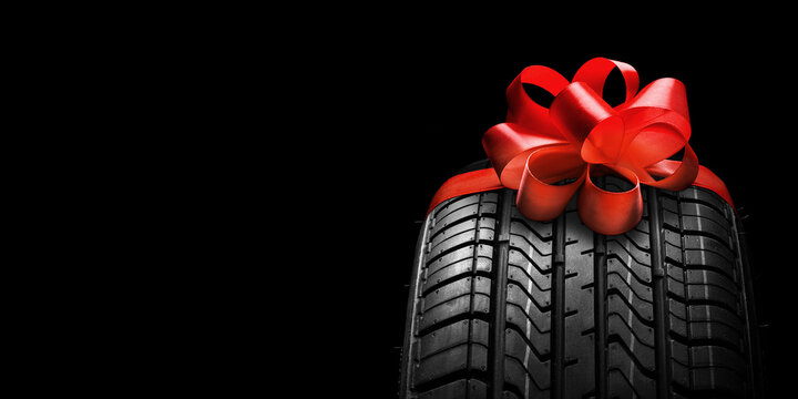 a black isolation rubber tire, on the grey backgrounds in a bow for christmas