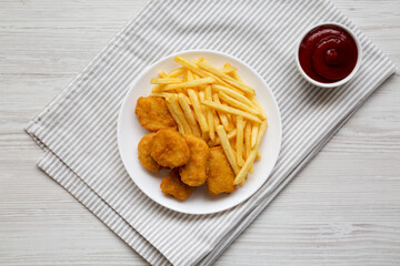 Tasty Fastfood: Chicken Nuggets and French Fries on a plate on a white wooden background, top view. Flat lay, overhead, from above.