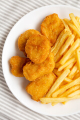 Tasty Fastfood: Chicken Nuggets and French Fries on a plate on cloth, top view. Flat lay, overhead, from above.