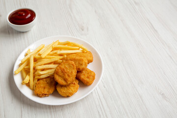 Tasty Fastfood: Chicken Nuggets and French Fries on a plate on a white wooden background, low angle view. Copy space.