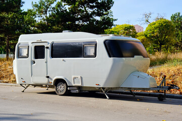 White camping trailer parked on the road. Affordable housing or vacation.