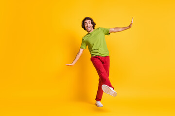 Fototapeta na wymiar Full length body size photo funny carefree man wearing red pants sneakers dancing pretending plane isolated vivid yellow color background