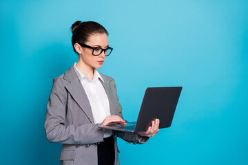 Portrait of attractive focused lady geek IT expert holding in hands laptop working isolated over bright blue color background